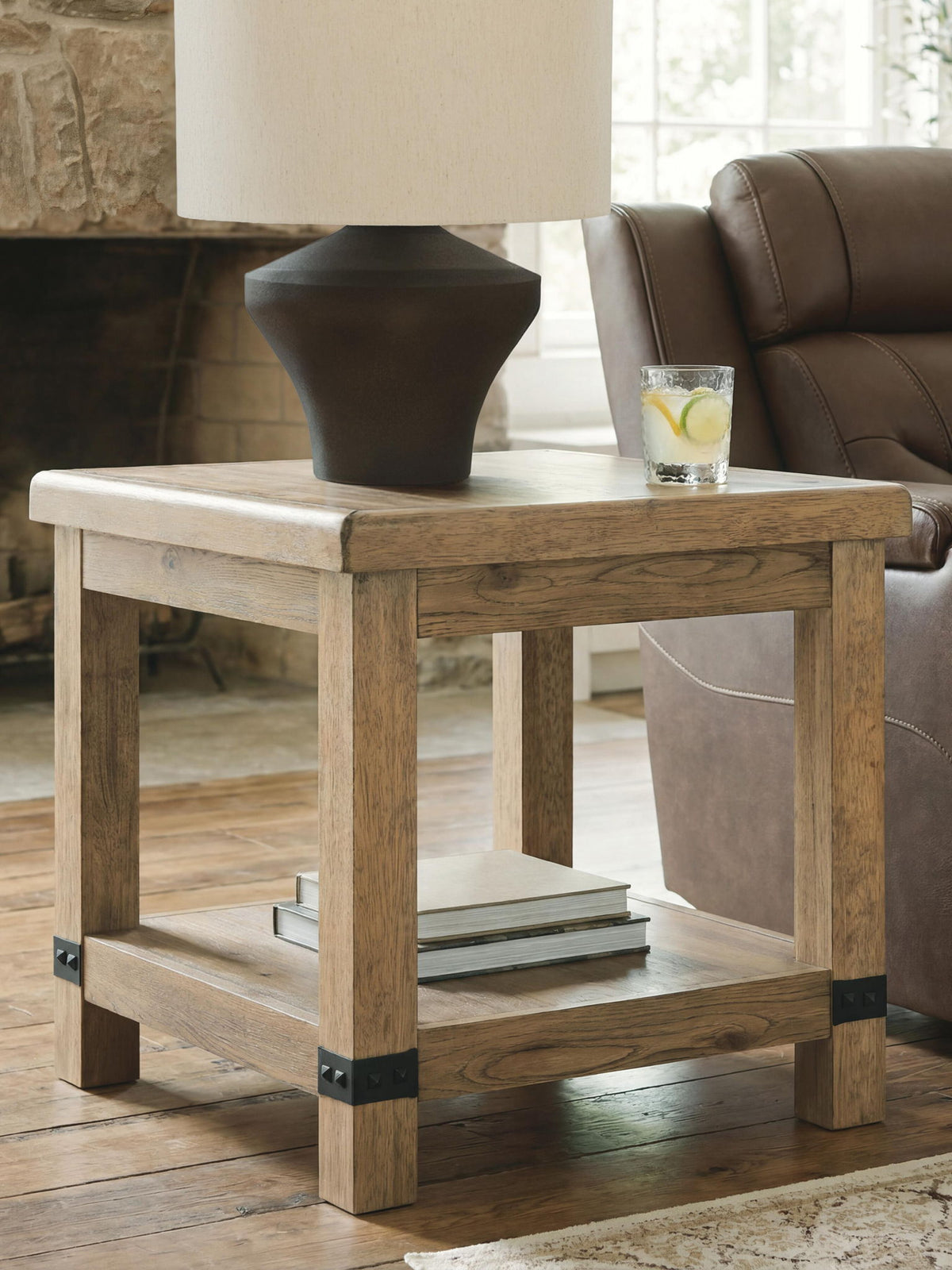 Wooden side table with a lamp and glass of lemonade in a living room setting.
