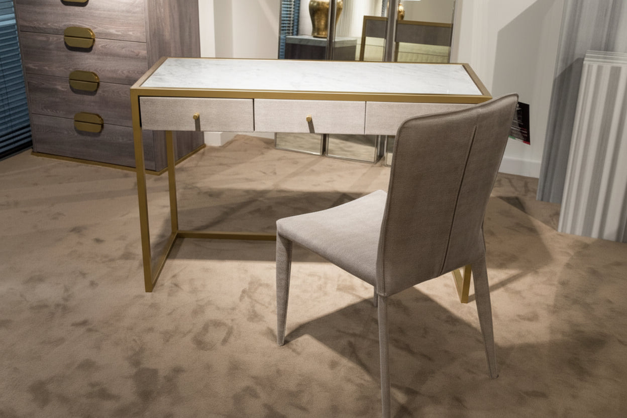Modern desk with glass top and gold legs in a room setting