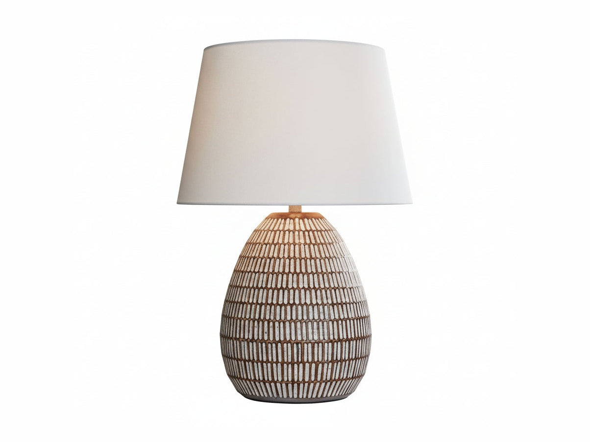 The Darrich wicker lamp on a table with a couch and decorative items in the background.