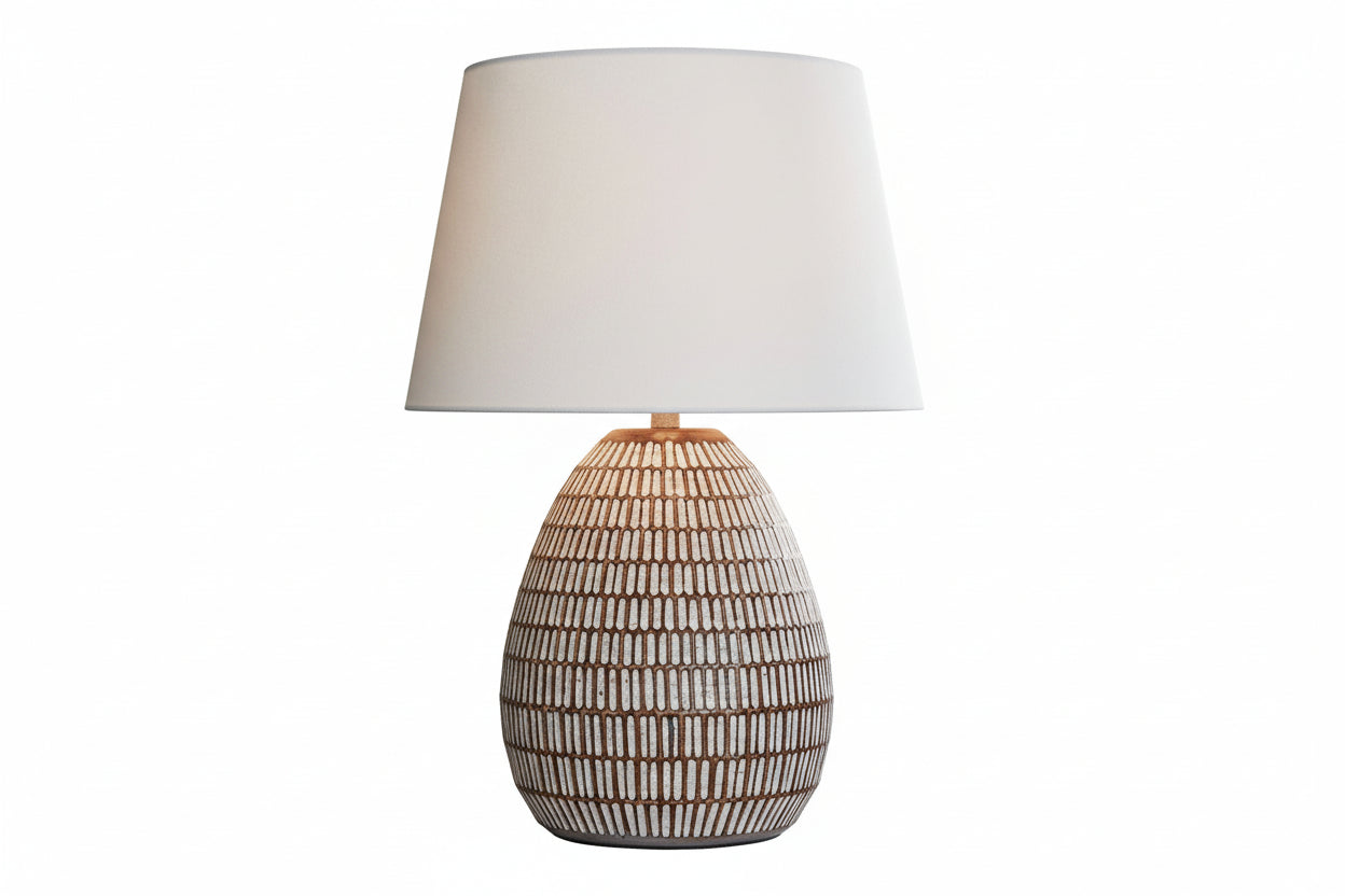 The Darrich wicker lamp on a table with a couch and decorative items in the background.