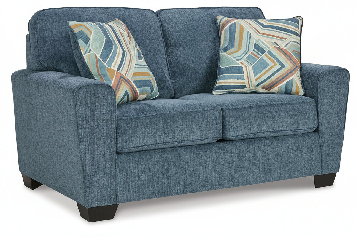 A blue upholstered loveseat with two patterned throw pillows, shown on a clean white background.