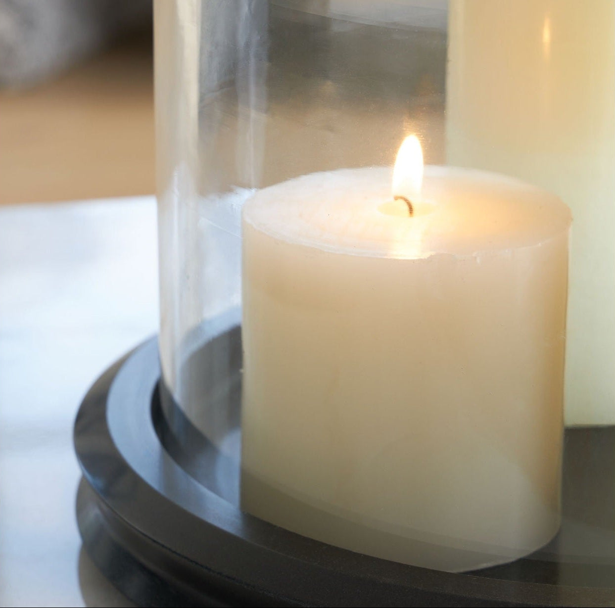 Candle in a glass lantern on a reflective surface
