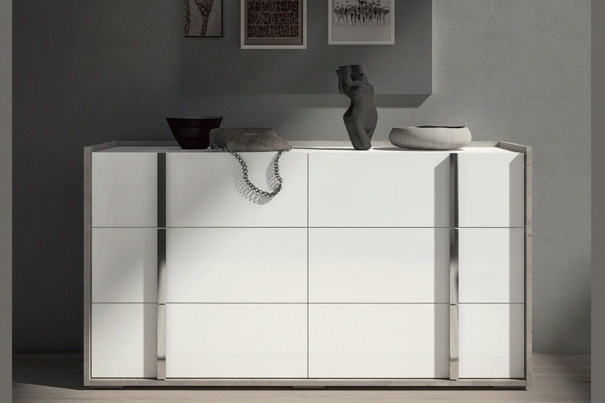 A modern white high-gloss cabinet with mirrored glass doors and slim metallic side handles, styled in a minimalist room with decorative vases on top.