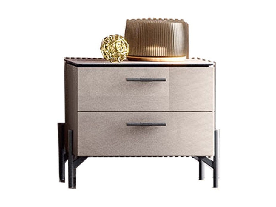 A modern two-drawer nightstand with textured taupe-beige drawer fronts, dark metal legs, and black drawer pulls, styled with a ribbed gold lamp and a decorative gold orb on top, set against a plain white background.