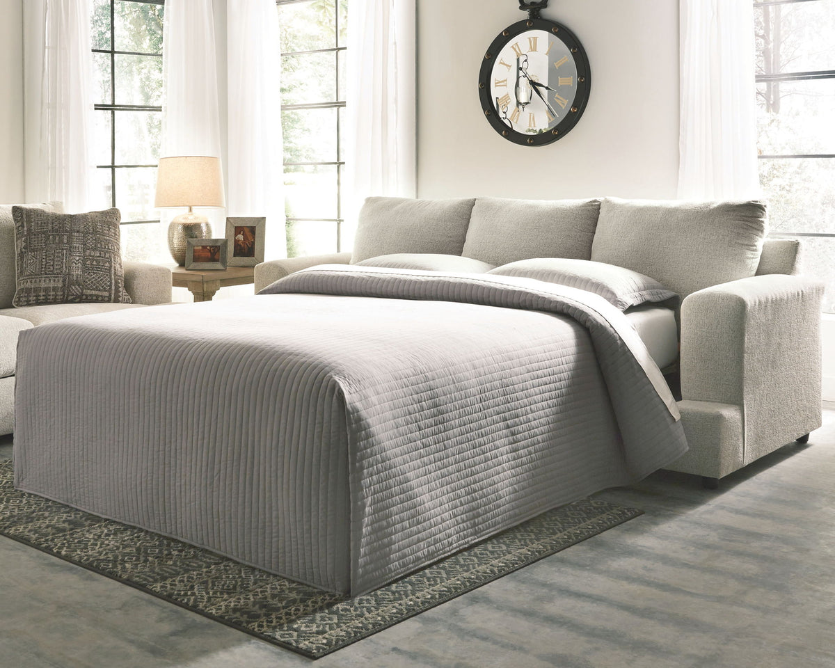 Gray sofa bed in a living room setting with a clock on the wall.