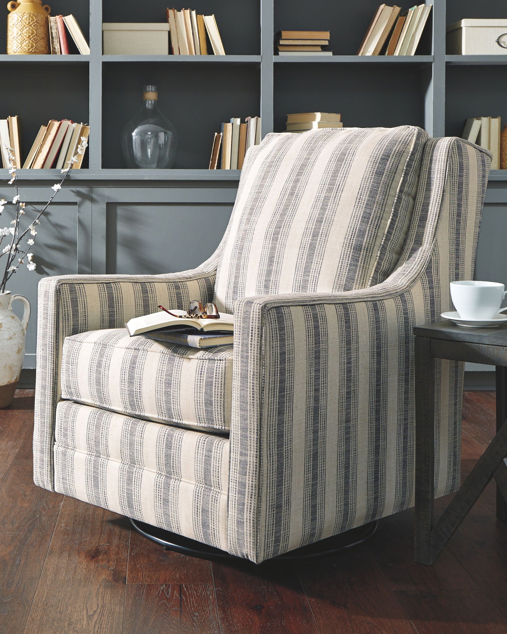 Striped armchair in a room with bookshelves and a table.