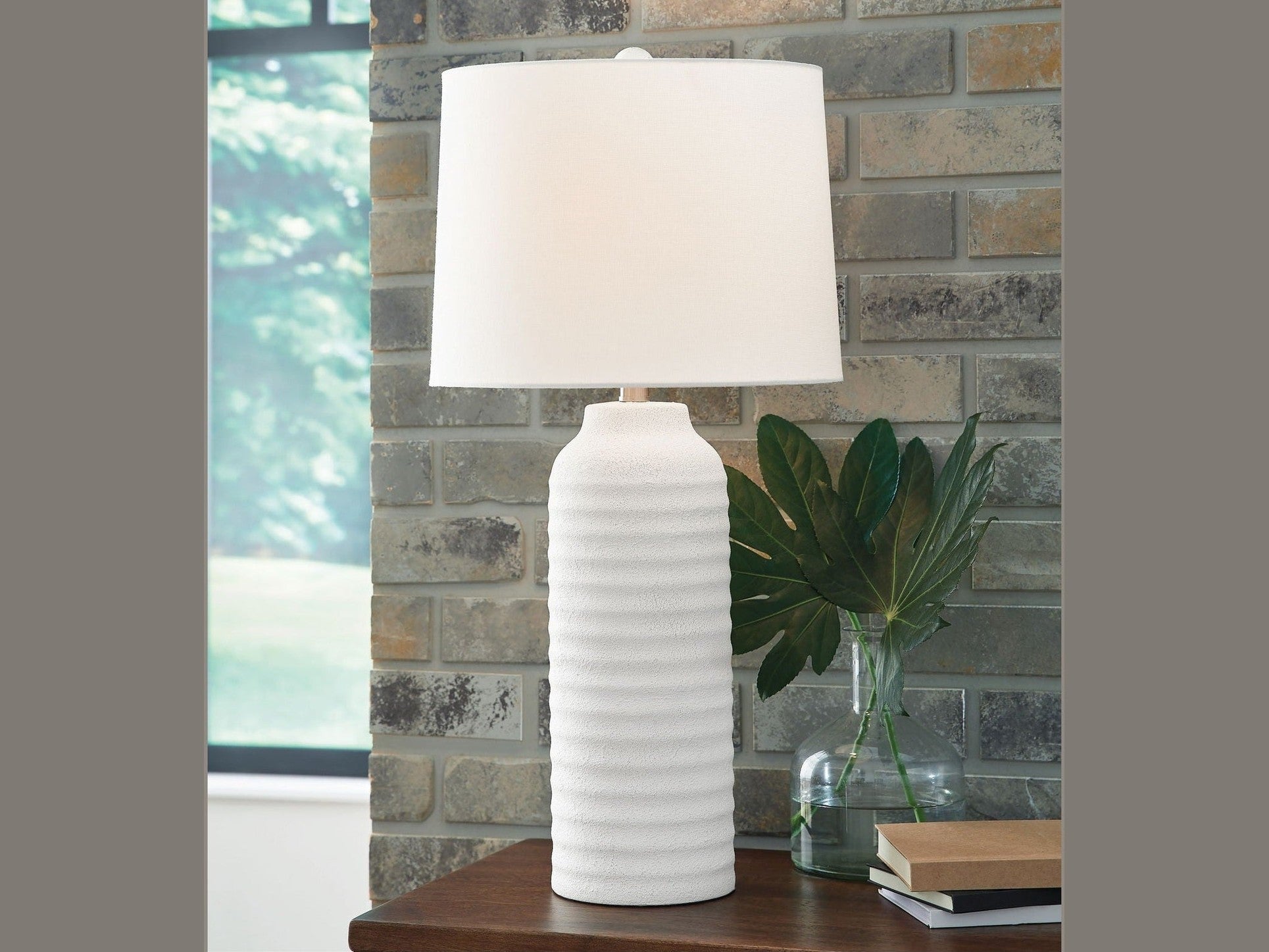 White table lamp on a wooden surface with a stone wall background