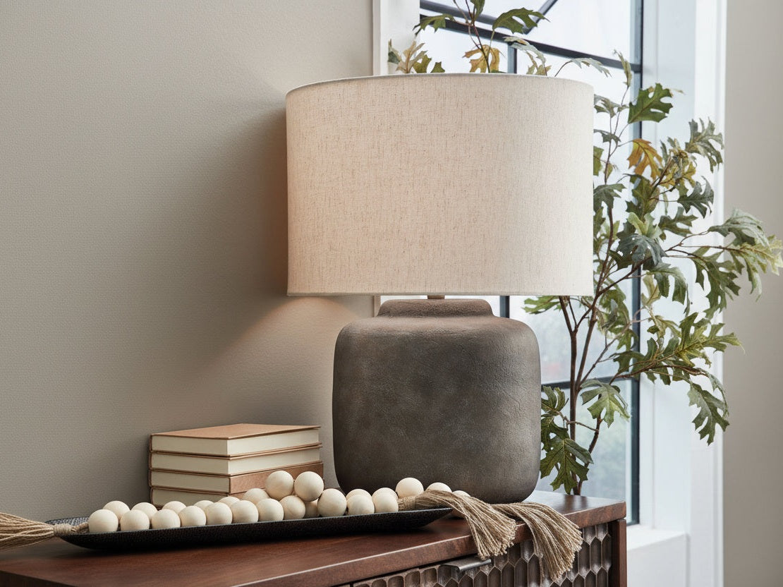 Zandophen table lamp with a beige shade and brown base on a wooden surface, with books and decorative items in the background.