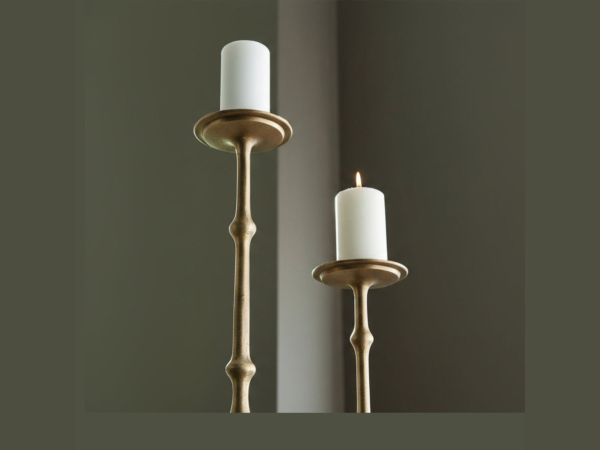 Two gold candle holders with white candles against a dark background