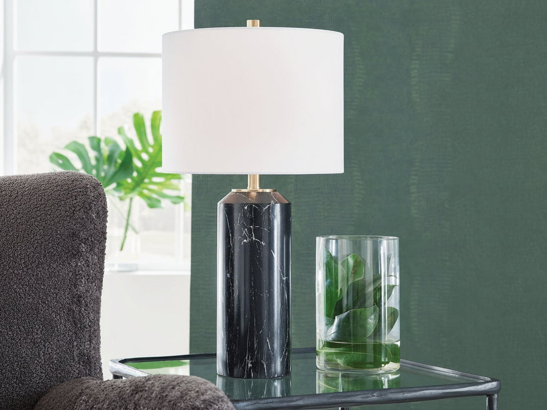 Hanzila decorative lamp with a black marble base and white shade on a table with a green plant in the background.