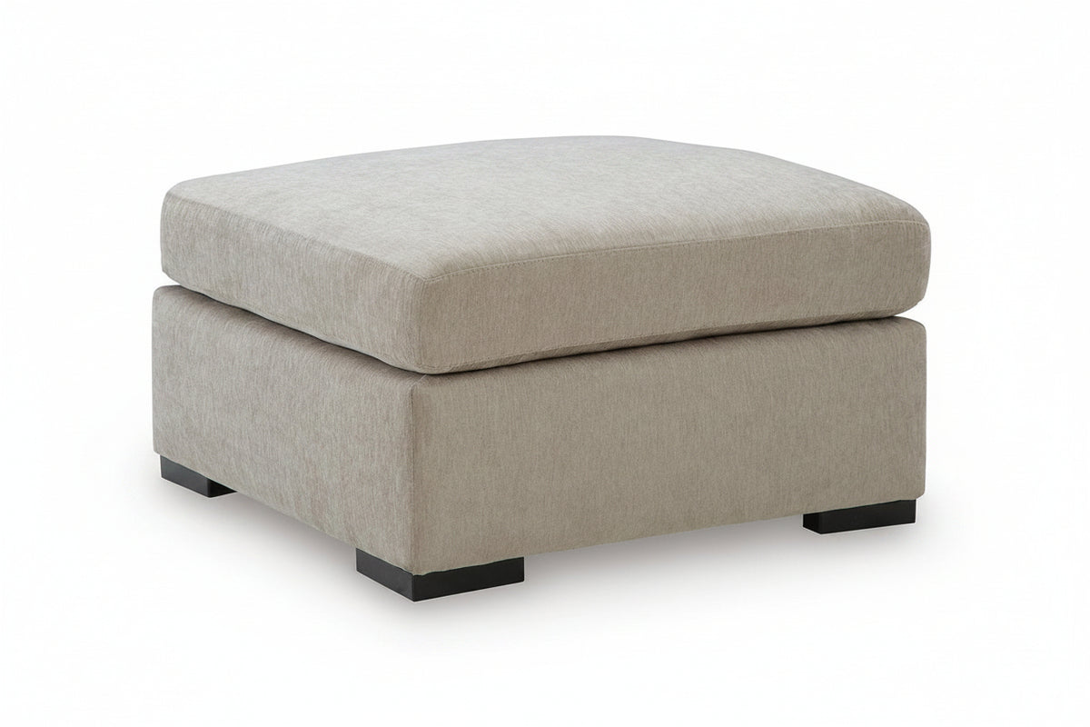 A square upholstered ottoman with a two-tiered design, featuring a textured light beige fabric and black block feet, shown on a white background.