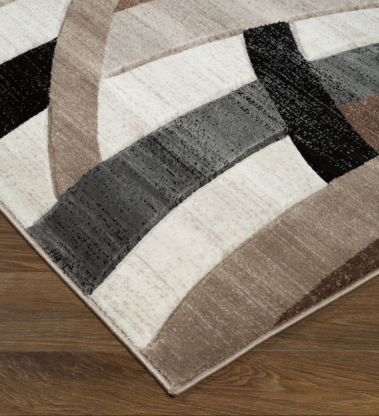 Geometric patterned rug with brown, black, and white colors on a wooden floor.
