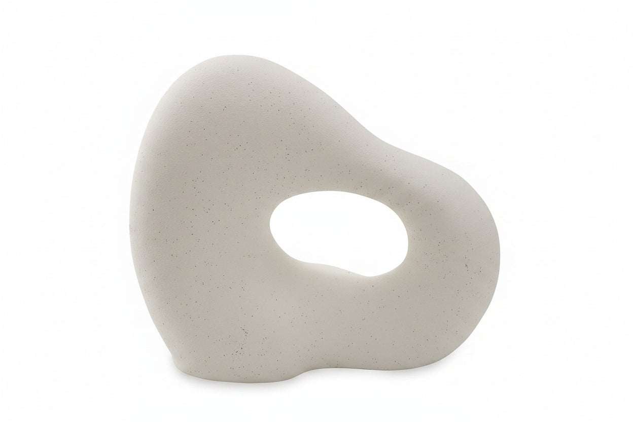 White ceramic sculpture with a circular hole on a white background