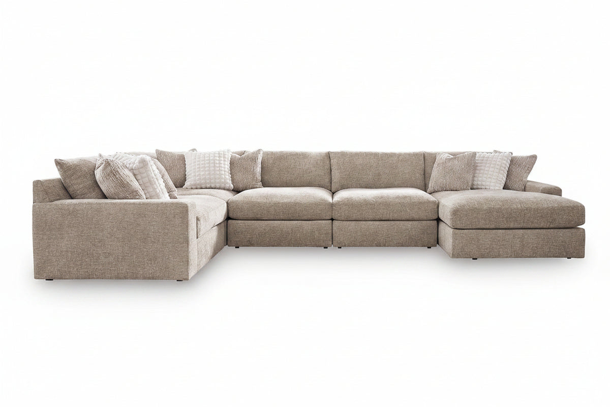 A light beige upholstered sectional sofa with a left-facing chaise and multiple matching accent pillows, shown on a clean white background.
