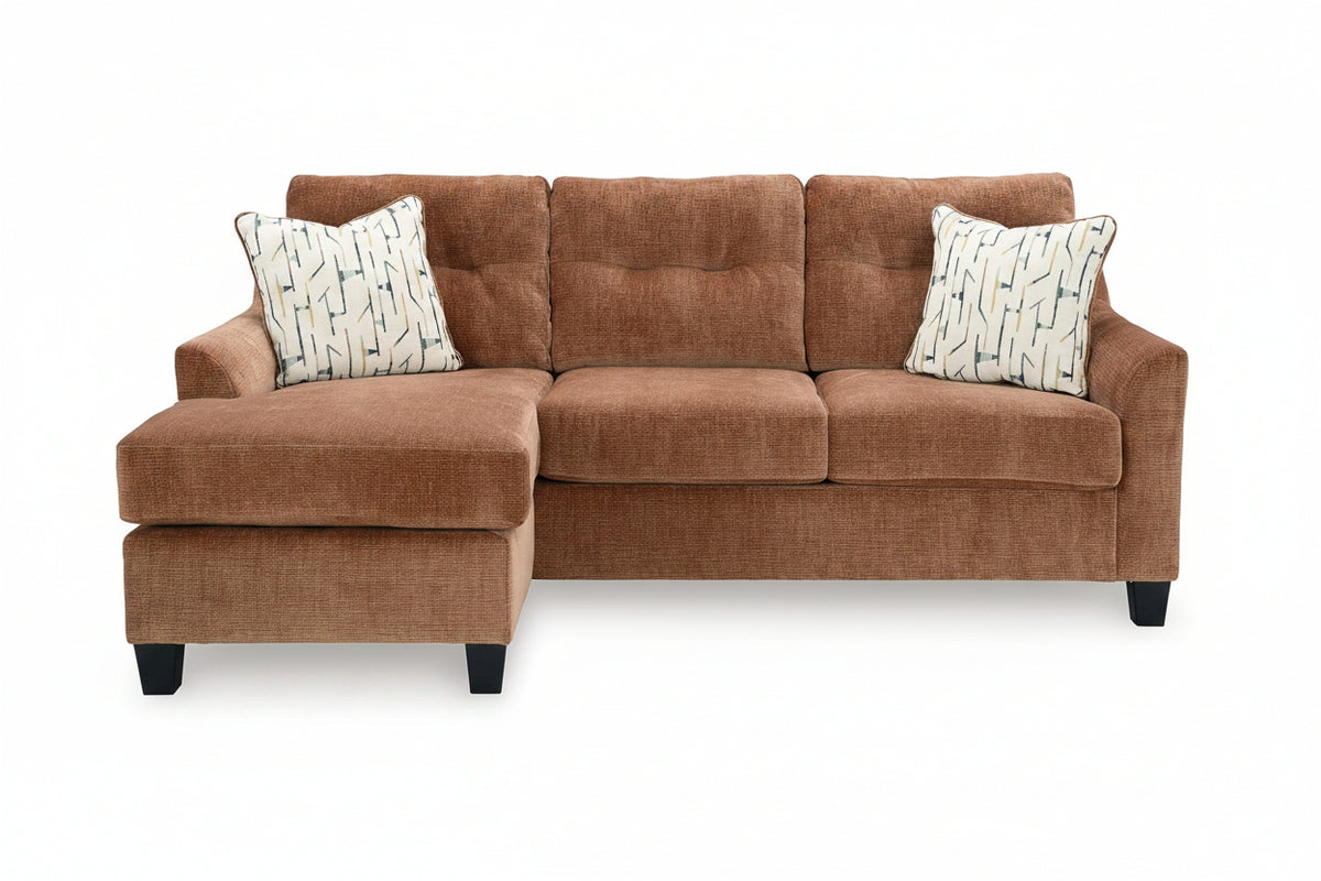 A three-seater sectional sofa with a left-facing chaise lounge, upholstered in a textured rust-brown fabric. It features two decorative throw pillows with a white background and a blue geometric pattern, set against a plain white background.