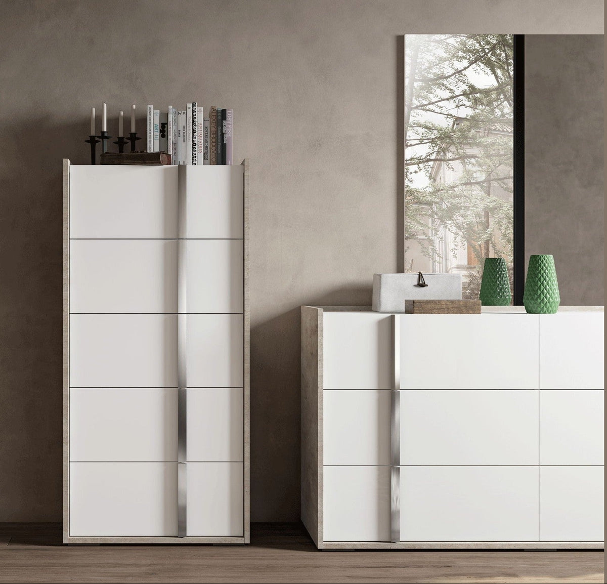 A modern white bedroom furniture set featuring a tall wardrobe with sliding doors and a matching chest of drawers, styled against a textured gray wall with a mirror and decorative items.
