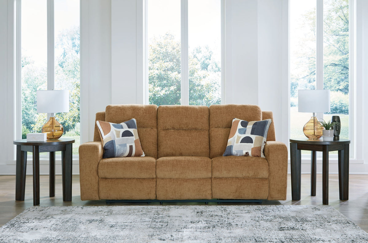 Brown sofa with patterned cushions in a living room setting with large windows.