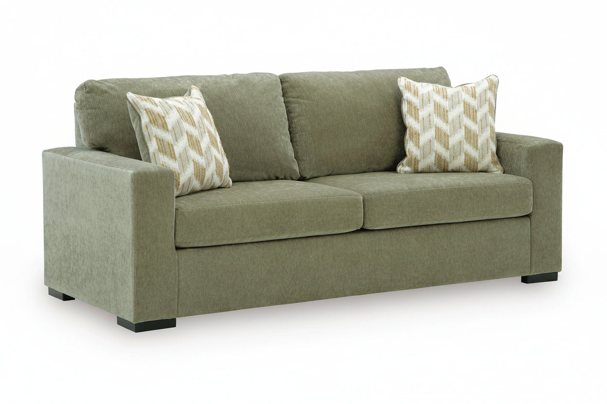 An olive green upholstered loveseat sofa with two patterned throw pillows, shown on a plain white background.