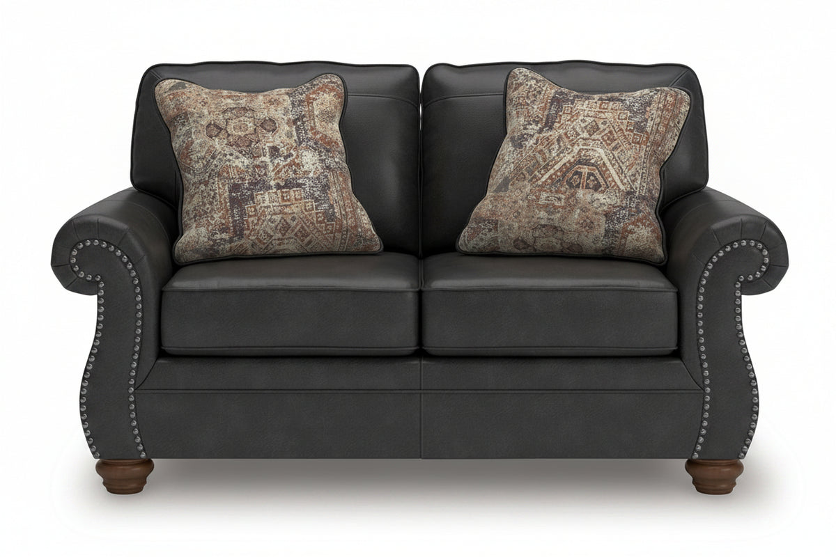 Black leather sofa with patterned pillows on a white background