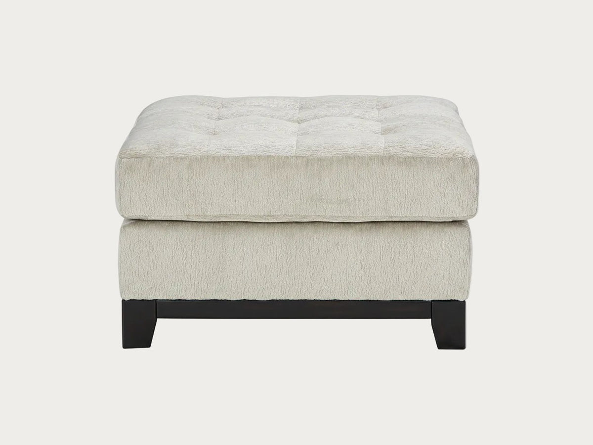Beige ottoman with tufted design on a white background