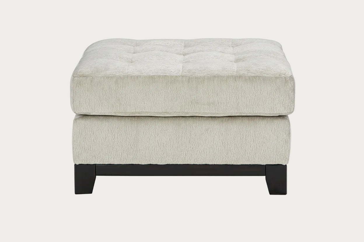 Beige ottoman with tufted design on a white background