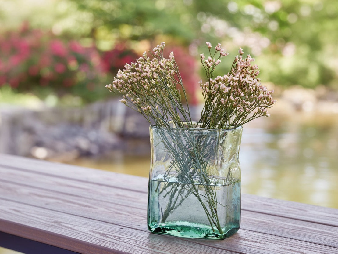 Taylow green glass vase with dried flowers on a wooden surface outdoors