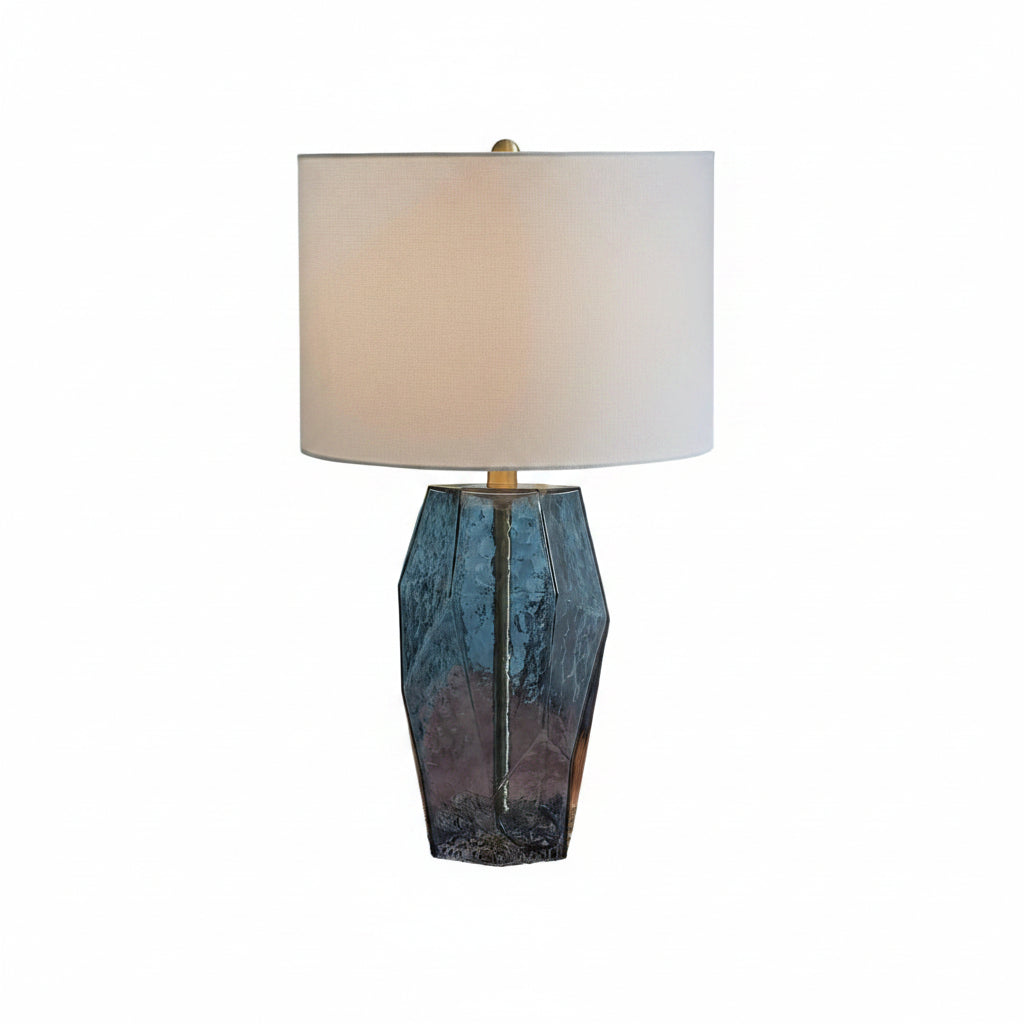 Decorative lamp on a textured stool with a patterned wall and chair in the background