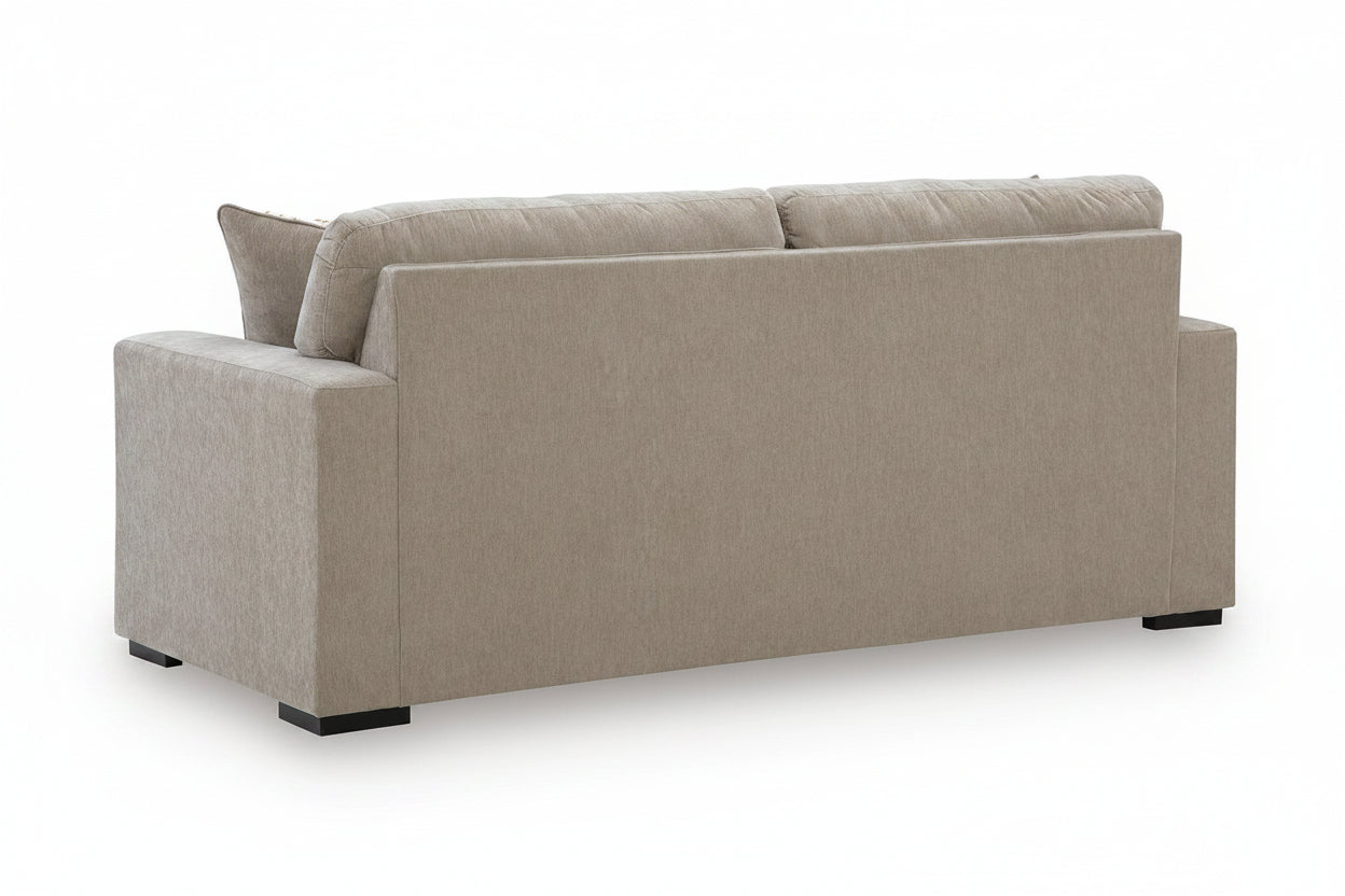 A light beige upholstered loveseat or sofa shown from a three-quarter rear angle on a clean white background.