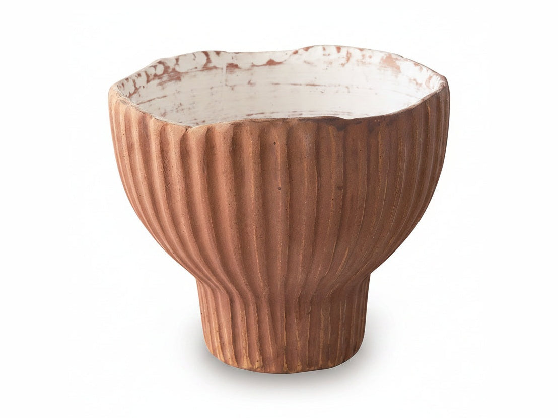 Terracotta-colored ceramic bowl with ribbed texture on a white background