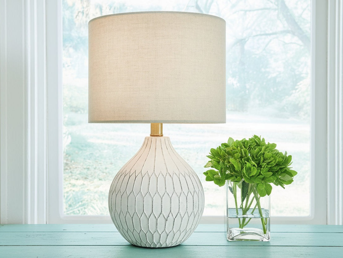 Wardmont white textured table lamp with beige shade on a surface near a window with a plant in the background.