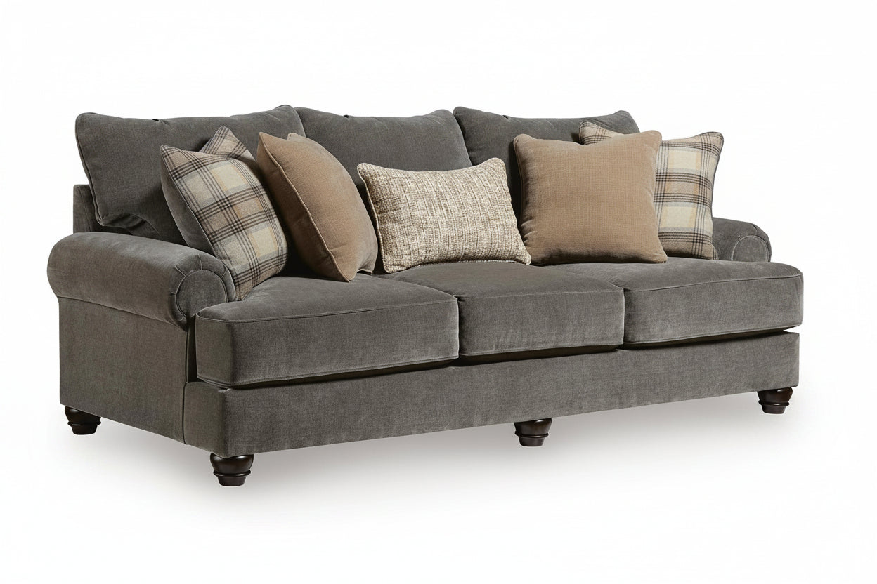 A three-seat upholstered sofa in dark gray fabric, styled with five throw pillows including two plaid and two solid beige and textured neutral designs, shown on a white background.