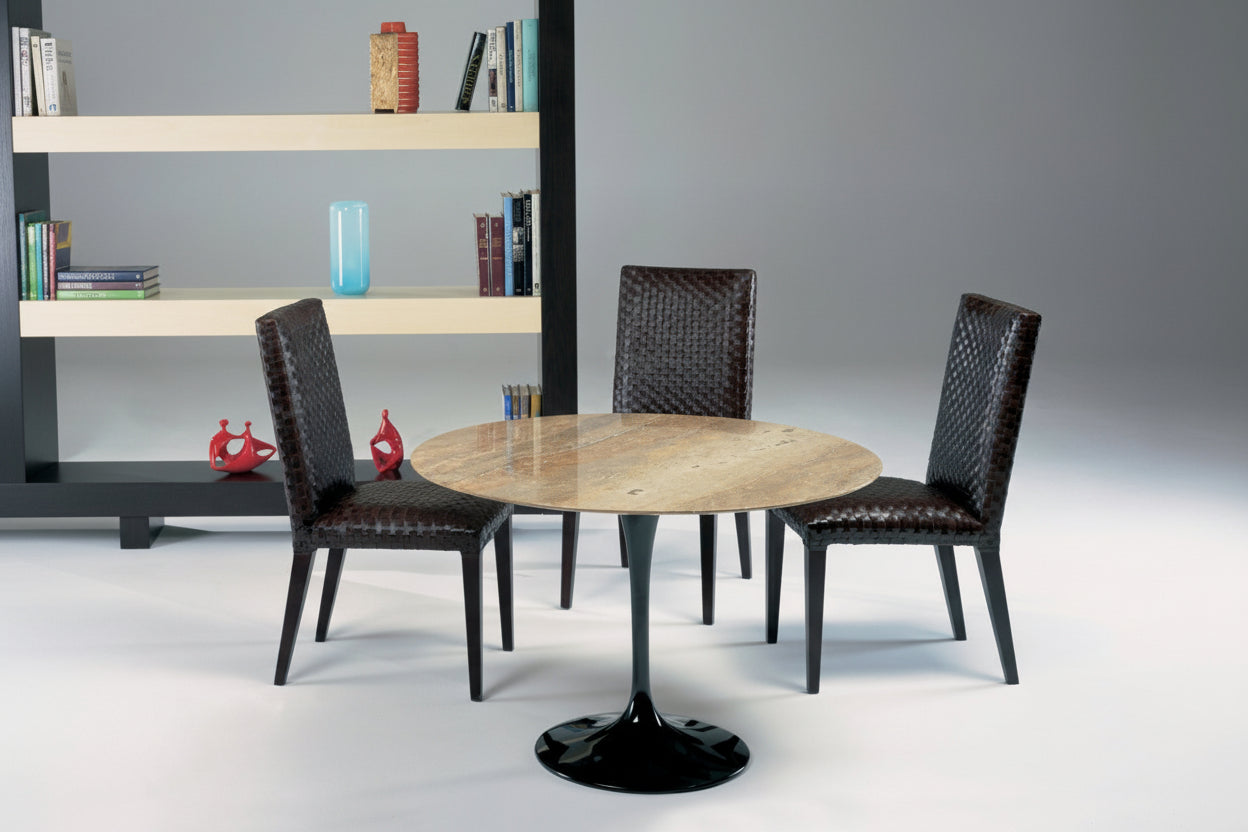 Round dining table with four chairs in a modern interior setting.
