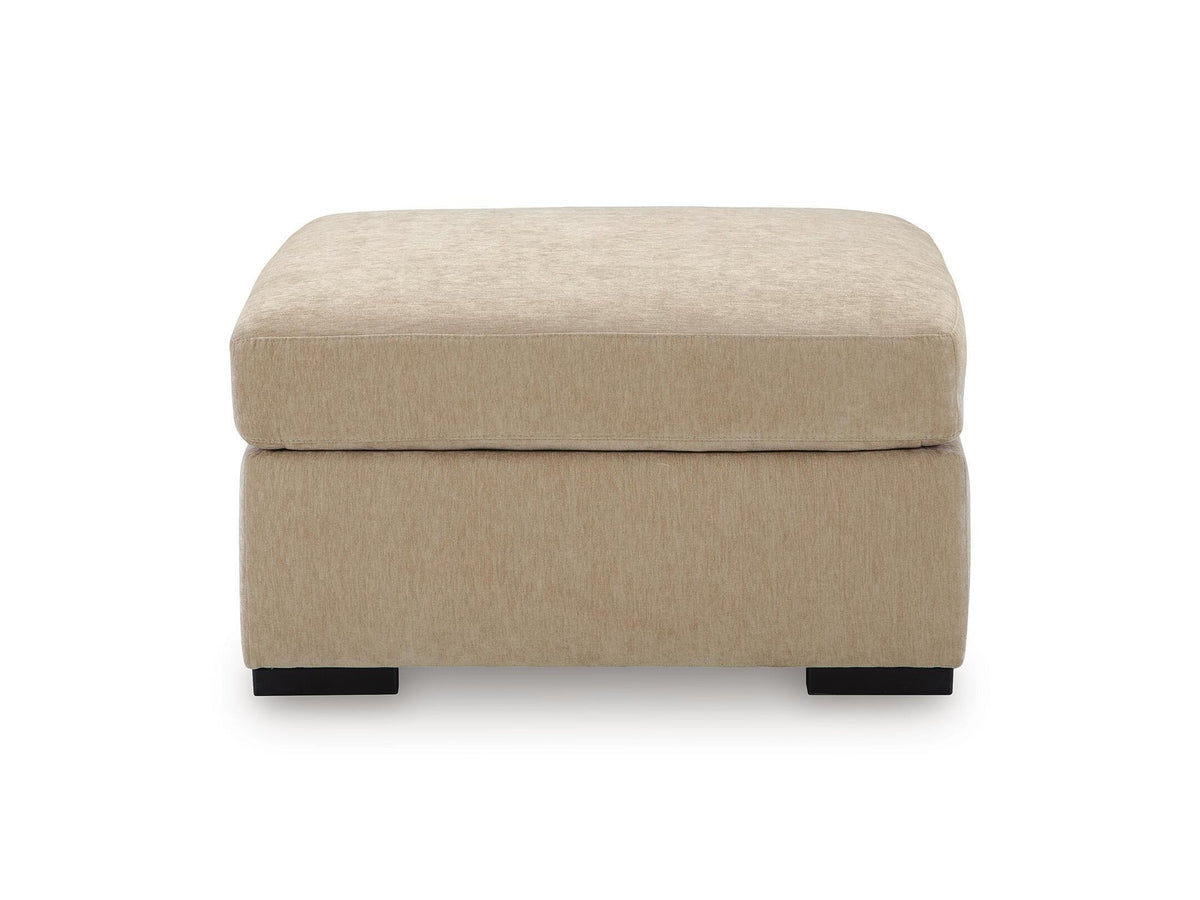 A square upholstered ottoman in a textured beige fabric, featuring a thick cushioned top and a solid base, supported by two small dark legs, shown against a plain white background.