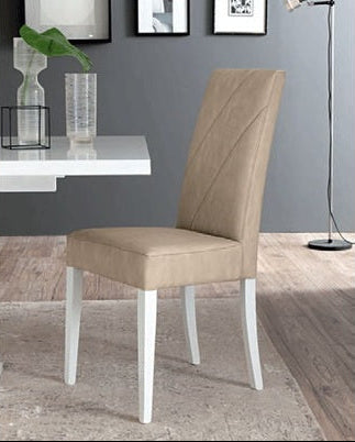 A beige upholstered dining chair with white legs, positioned in a modern dining room setting next to a white table.