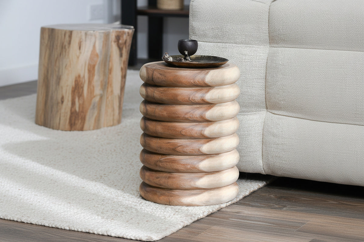 Stacked wooden rings side table with a decorative bowl on top, next to a sofa.