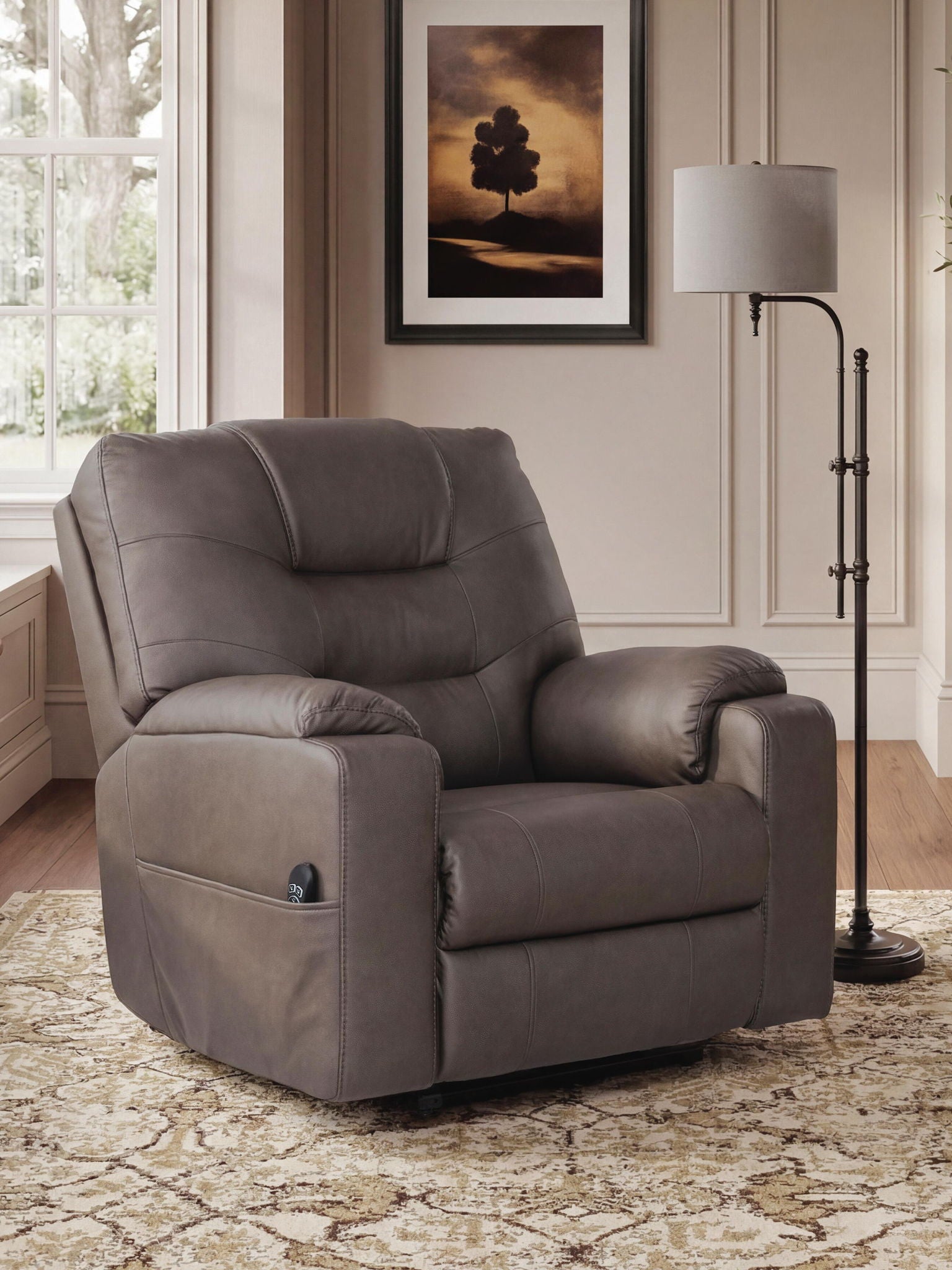 A gray upholstered recliner chair shown in a styled living room setting with a patterned rug, floor lamp, window, and framed wall art.