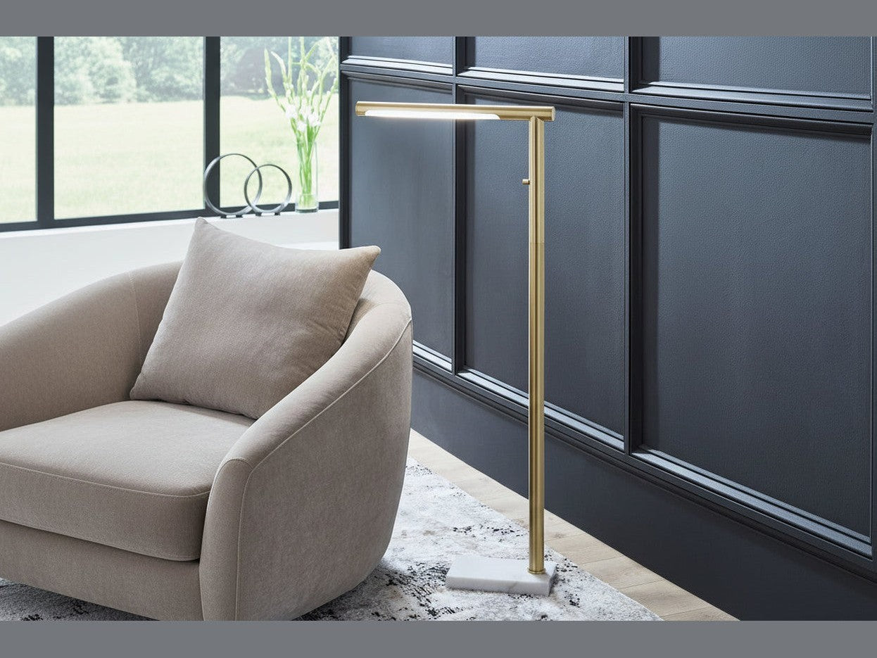 The Santiford gold floor lamp next to a beige sofa in a modern living room.