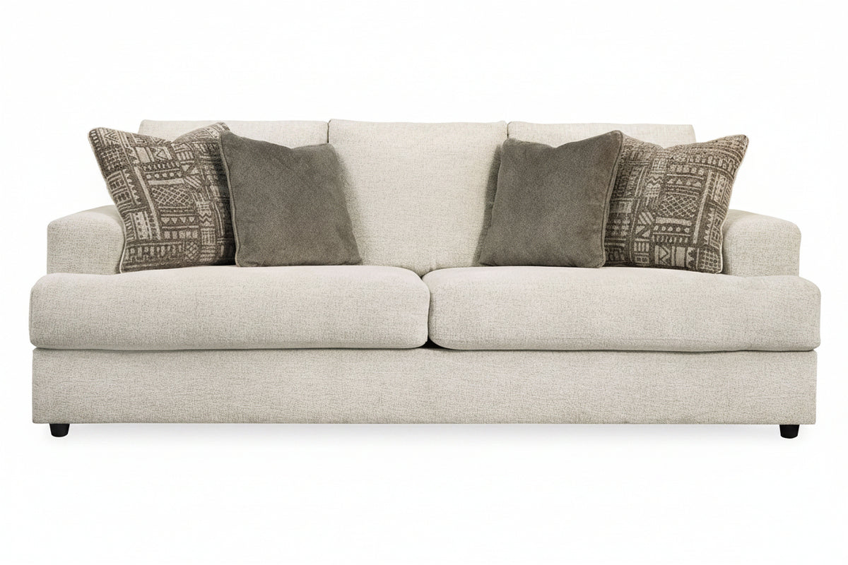 Beige sofa with patterned and solid gray pillows on a white background