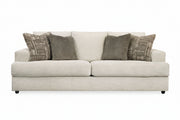 Beige sofa with patterned and solid gray pillows on a white background