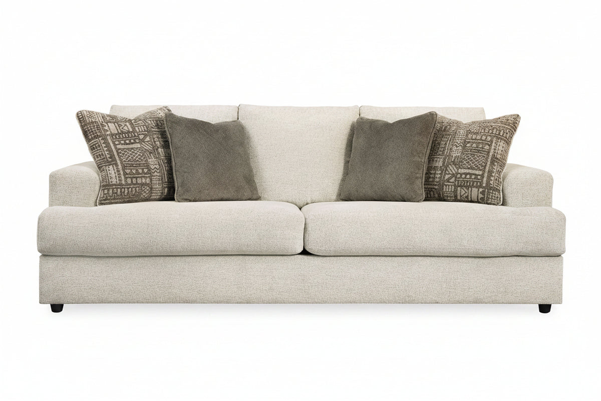 Beige sofa with patterned and solid gray pillows on a white background