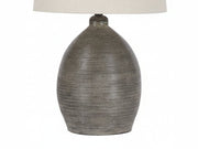 Joyelle table lamp with textured ceramic base and beige lampshade on a white background.