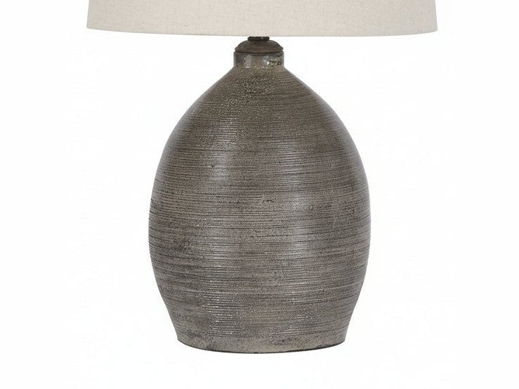 Joyelle table lamp with textured ceramic base and beige lampshade on a white background.