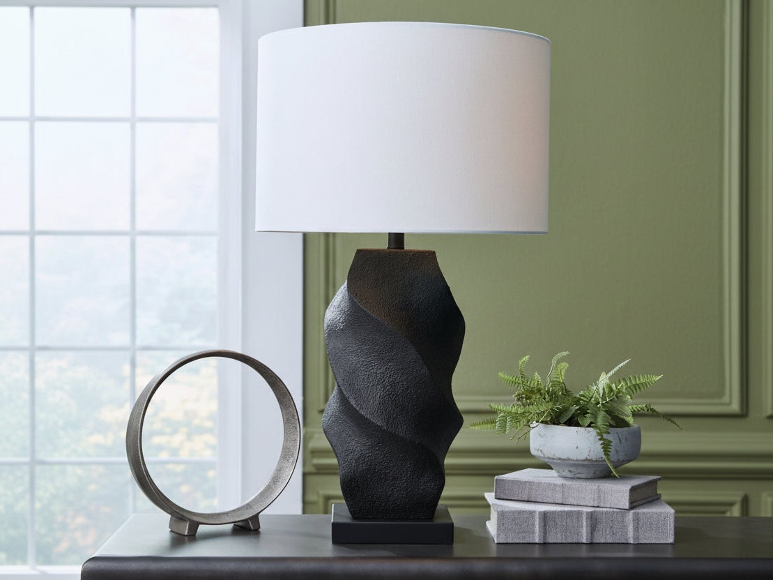 Amillion decorative table lamp with a textured base on a surface with a plant and books in the background.