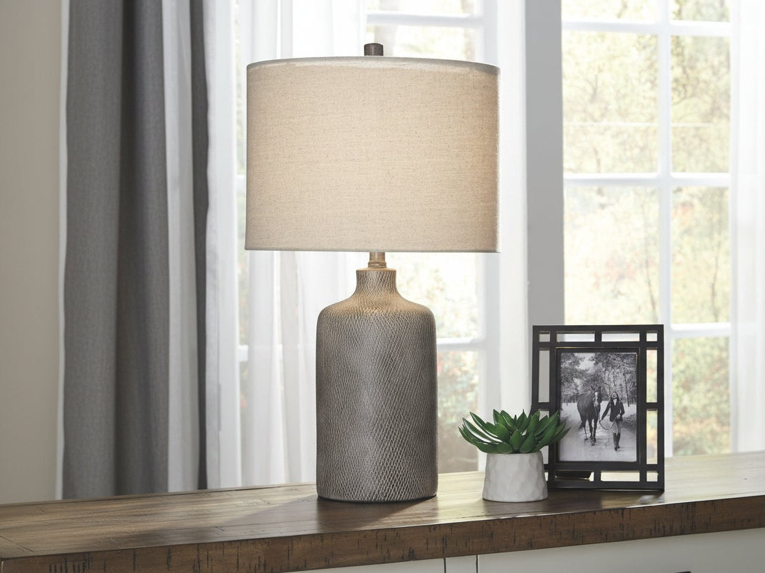 Linus table lamp with textured base and beige shade on a wooden surface with a blurred background