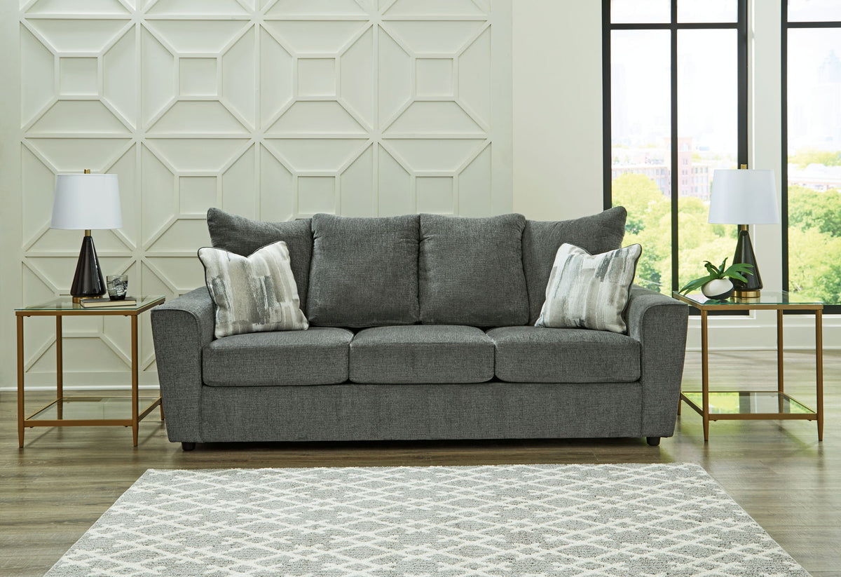 Gray sofa in a living room with decorative pillows and side tables.
