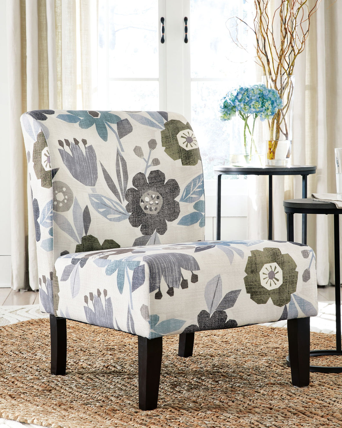 Floral patterned armchair in a room with a table and flowers.