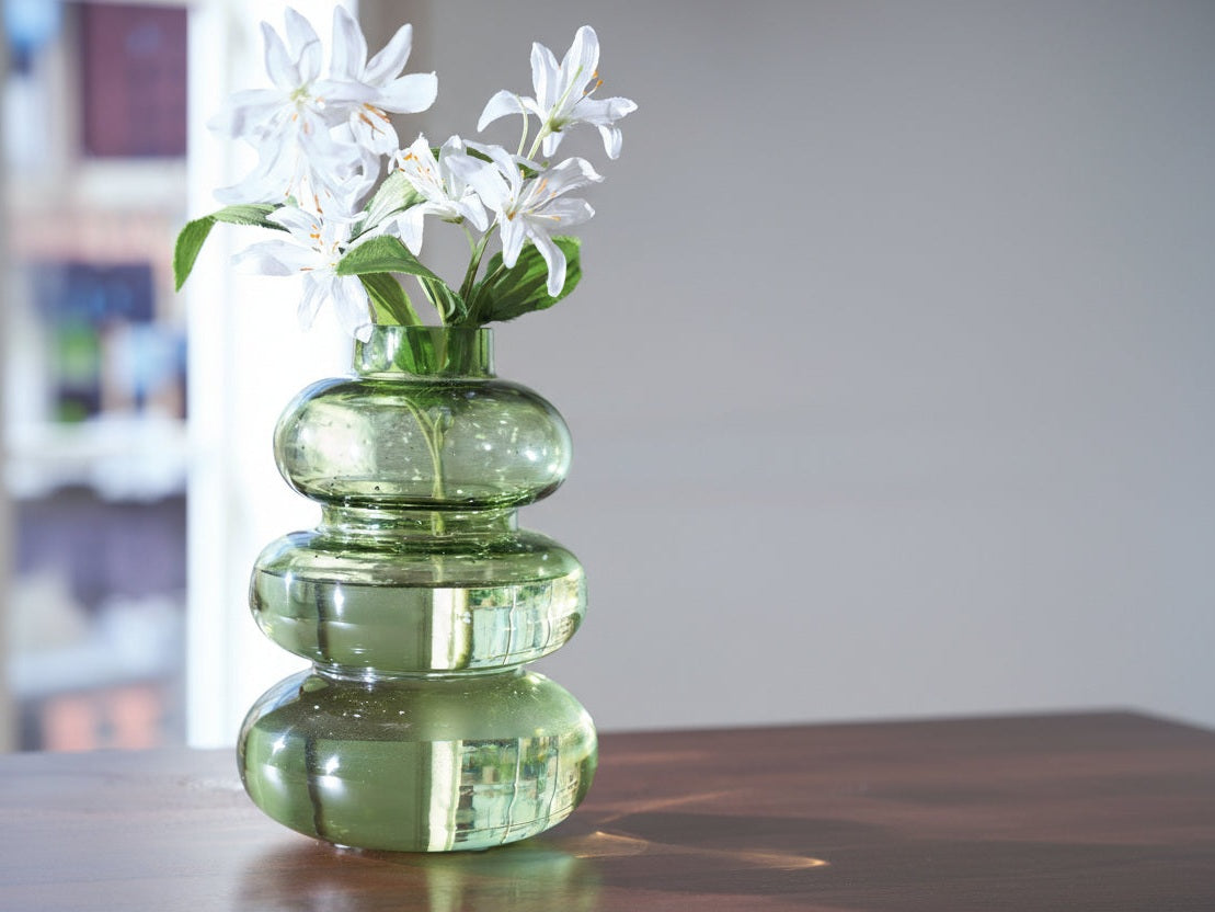 Renethorne green glass vase with white flowers on a blurred background.