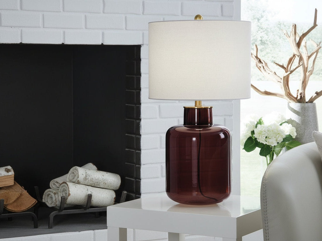 Mette table lamp with a brown glass base and white shade on a table.