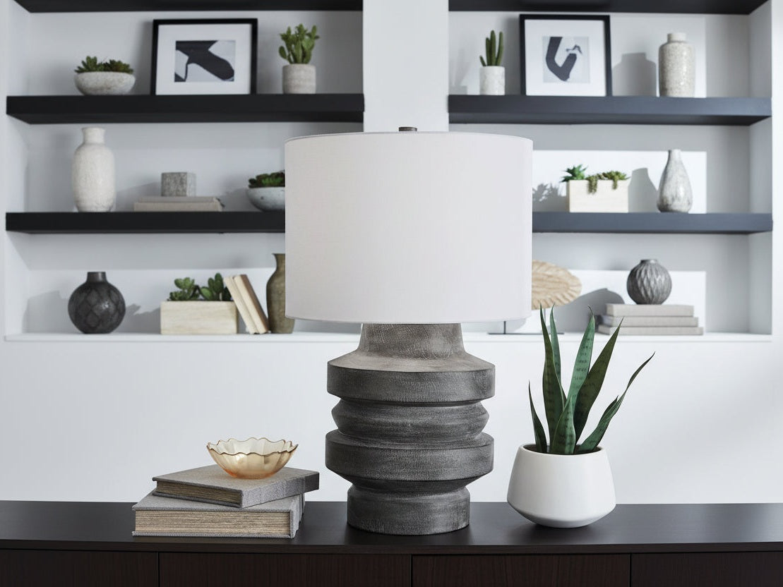 Wahida table lamp with a textured gray base and white shade on a dark surface.