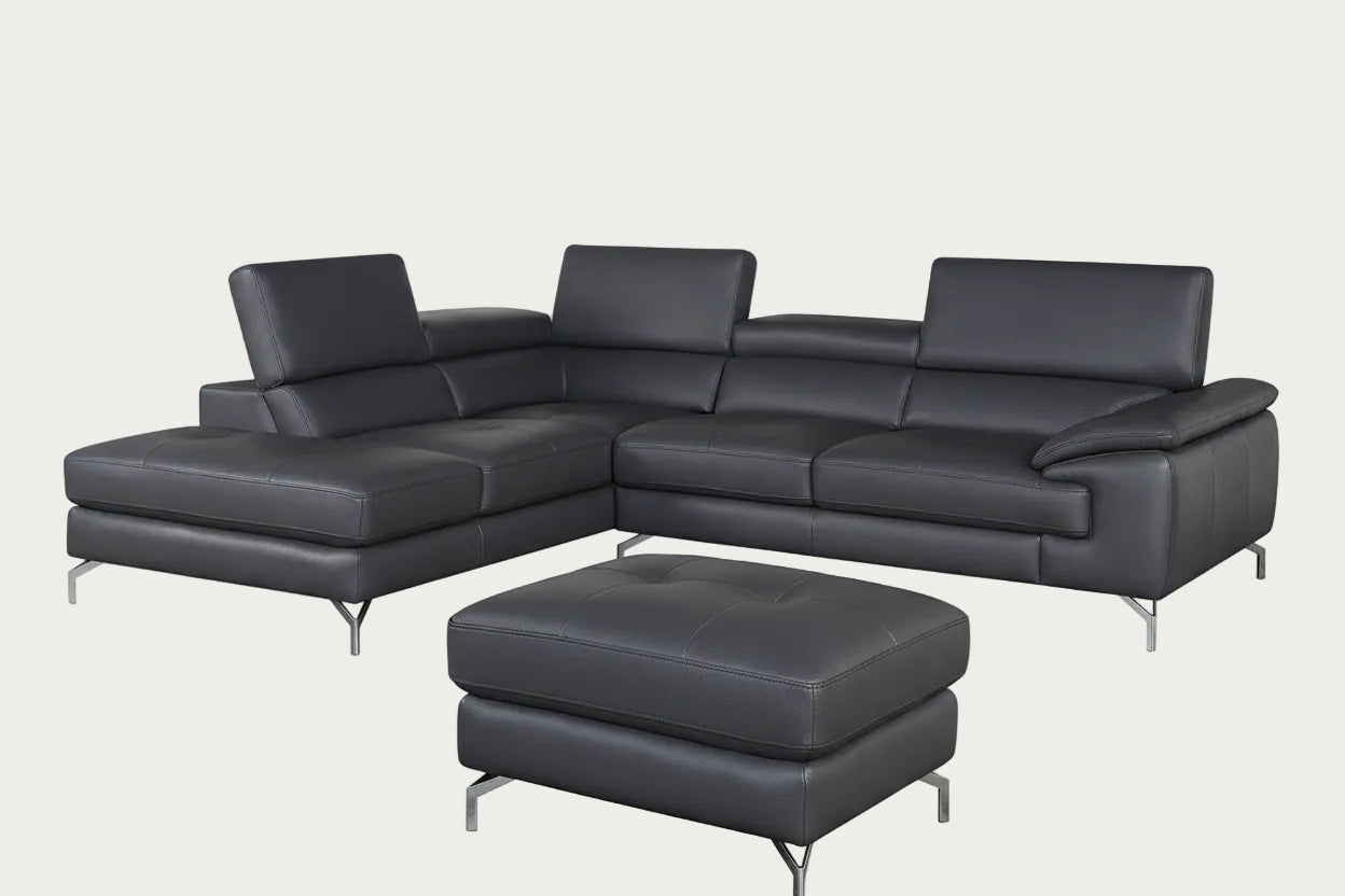 Gray leather sectional sofa with ottoman in a room with a gray wall and pendant light.
